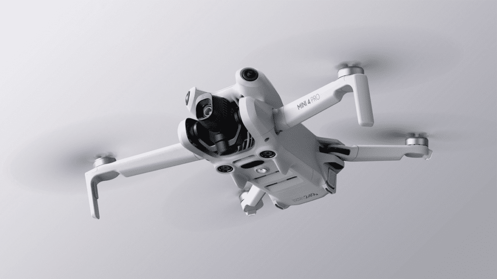 Imagem do DJI Mini 4 Pro em voo, destacando seu design leve de 249 gramas, ideal para manobras ágeis e exploração em espaços apertados.