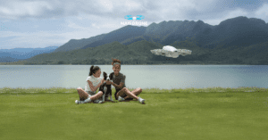 Um drone DJI Neo voando e duas meninas sentadas a grama admirando.