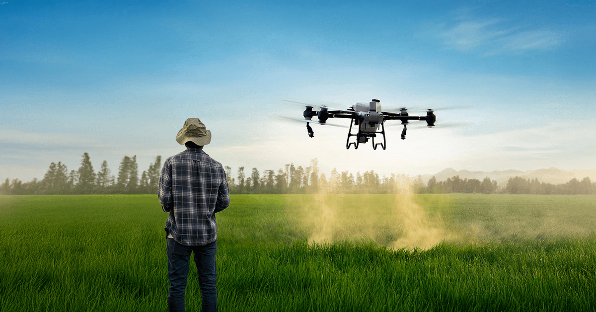 Um operador de drone agrícola operando seu drone em um campo verde.