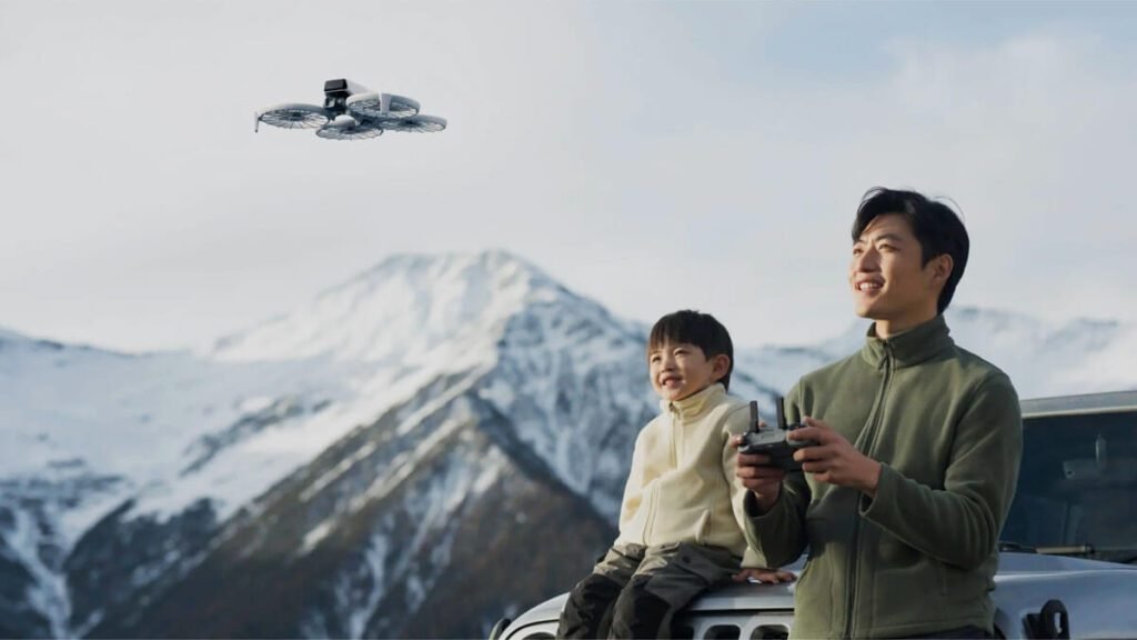 Homem e criança sorrindo enquanto pilotam o DJI Flip em um cenário de montanhas nevadas, destacando a experiência cinematográfica e a facilidade de uso do drone.