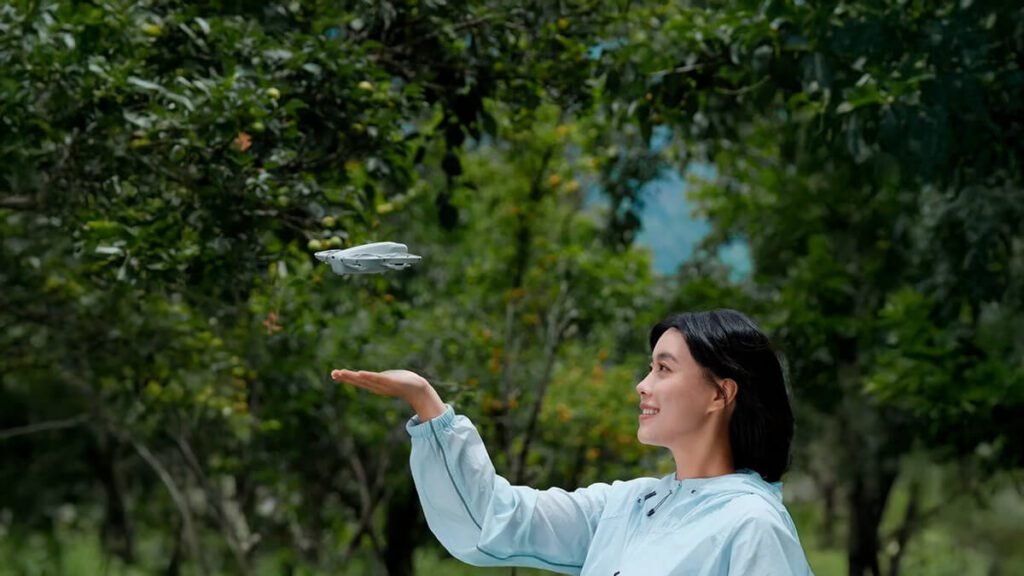 Mulher sorrindo enquanto lança o DJI Neo da mão, destacando a portabilidade e facilidade de uso do drone em um ambiente ao ar livre.